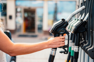 Closeup of woman pumping gasoline fuel in car at gas station. Petrol or gasoline being pumped into...