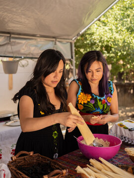 Indigenous sisters making tamales in an outdoor kitchen