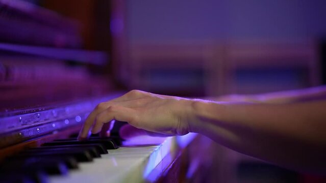 Woman Professional pianist hands playing on a wooden old grand piano close-up. Piano keys close up in dark violet colors. Student trains to play the piano Slow motion