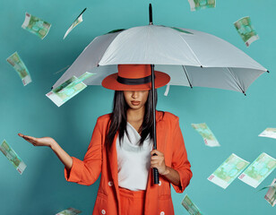 Money, fashion and rich lady being showered by cash while holding umbrella for insurance, protection and cover showing her wealth after payout. Winning luxury woman with dollar bills in the air