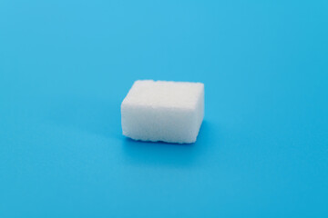 One sugar cube on blue background