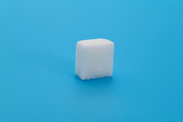 One sugar cube on blue background