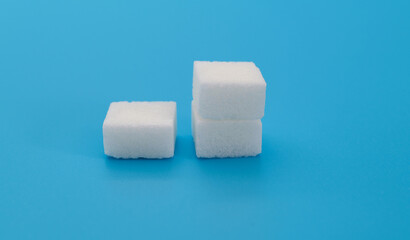 Three sugar cubes on blue background