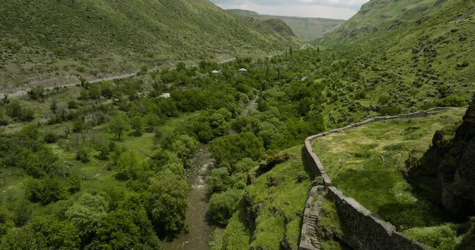 Dense Vegetation And River With Khertvisi Fortress On Rocky Hill In Meskheti, Georgia. Aerial Pullback Shot