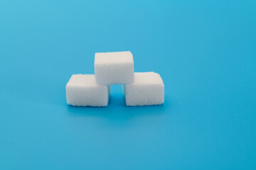 Three sugar cubes on blue background