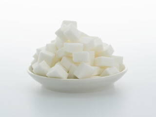 Sugar cubes on a plate on white background