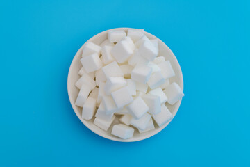 Sugar cubes on a plate on blue background