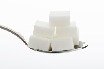 Sugar cubes in a spoon on white background