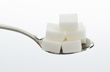 Sugar cubes in a spoon on white background