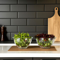 Fresh vegetables and salad bowls on kitchen wooden counter, front view