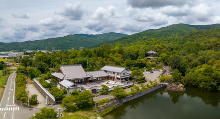 Aerial view of traditional Japanese building between forest and road on sunny day