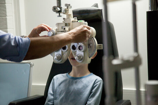 Young boy at an optometrist appointment looking through phoropter