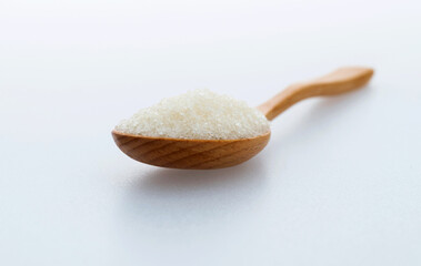 Wooden spoon with sugar crystals on white background