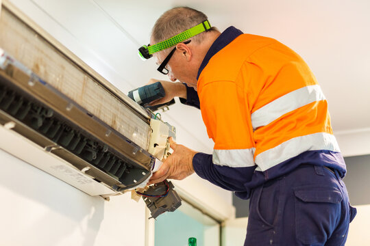 Tradie handyman in his fifties fixing an air con in home