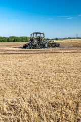 Obraz premium Feux de champs, carcasse de tracteur et d'un déchaumeur calciné suite à un incendie de chaumes lors de forte canicule