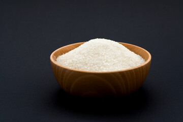 Granulated sugar in a bowl on black background