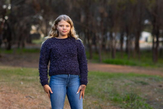 one girl wearing jeans and jumper standing outdoors by herself