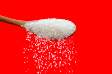 Sugar crystals falling out of wooden spoon
