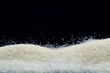 Pile of white sugar crystals on black background