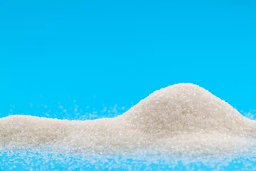 Fotobehang Pile of white sugar crystals on blue background © xy