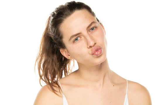 portrait of handsome young woman with folded lips waiting for kiss, standing over white background.