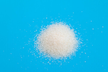 Obraz na płótnie Canvas Pile of white sugar crystals on blue background
