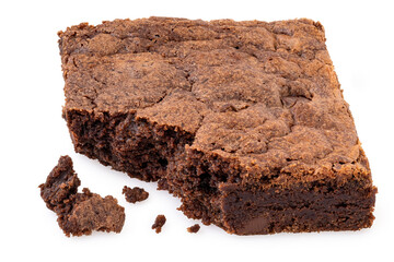 Chocolate brownie with chocolate chips next to crumbs isolated on white. Partially eaten.
