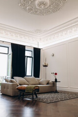 an example of a living room interior in a neo-classical style with modern elements. a sofa in the middle of a room with high ceilings and moldings.