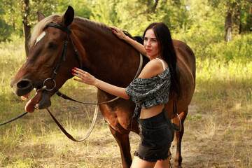 Young woman with a horse in the park