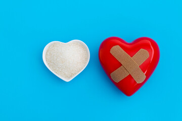 Red heart with bandage and a bowl of granulated sugar