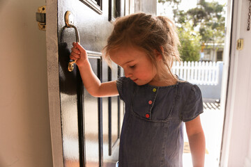 close up shot of a smiling girl wearing blue dress holding the door handle while looking down