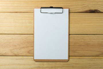 Blank wooden clipboard with paper on wood background copy space. Business, office supply, stationery concept.