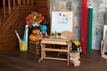 Interior of elementary school. Chalkboard, backpack, pencils and stationery on classroom. Teachers Day. Back to school. Empty classroom with blackboard and wooden table. Kindergarten. 
