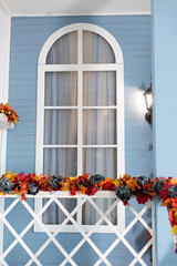wooden staircase railings decorated Fall festive yellow leaves, twigs and pumpkins. Entrance of...