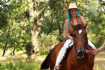 Woman with blue hair riding a horse