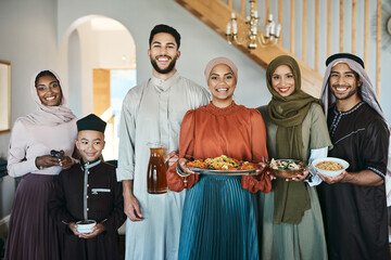 Smiling, festive muslim family celebrating eid or ramadan party lunch together holding dishes of...