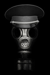 old gas mask in a military cap on a black background