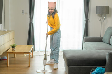 Young happy woman mopping and vacuum the floor in living room.