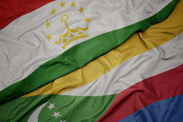 waving colorful flag of comoros and national flag of tajikistan.