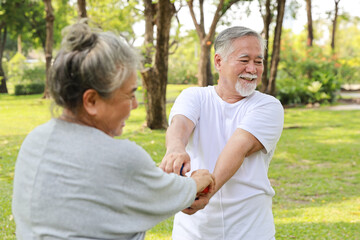 Happy and smiling asian senior couple doing arm work out and lifting dumbbell exercise with relaxation for healthy in park outdoor after retirement. Health care elderly outdoor lifestyle concept.