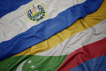 Fototapeta premium waving colorful flag of comoros and national flag of el salvador.
