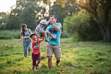 Fototapeta premium Happy young family: mother, father, two children son on nature having fun.