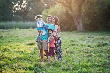 Fototapeta premium Happy young family: mother, father, two children son on nature having fun.