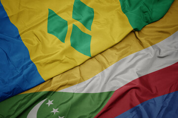 waving colorful flag of comoros and national flag of saint vincent and the grenadines.