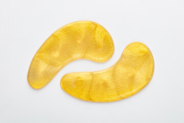 Gold hydrogel eye patches on white background.