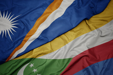 waving colorful flag of comoros and national flag of Marshall Islands .