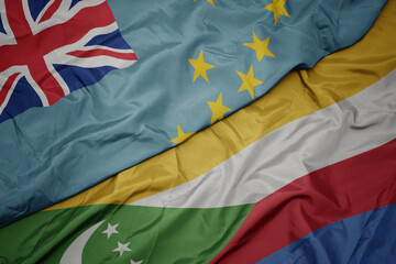 waving colorful flag of comoros and national flag of Tuvalu .