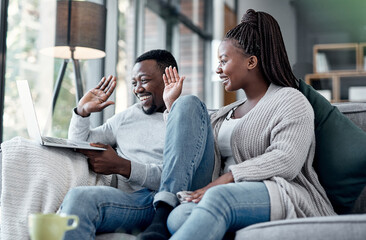 Happy couple waving while talking on video call and online chat on a laptop webcam in a lounge at...