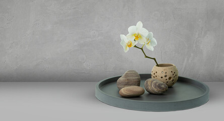 floral home decoration compostion with white orchid and stones on a plate, floral decoration concept with copy space for producht presentation