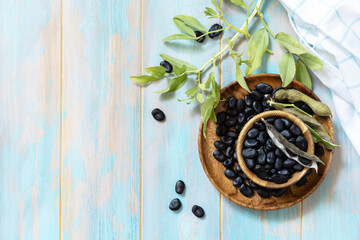 Raw organic vegetables. The concept of vegan or diet food. Fresh ripe black soy beans on a wooden table. View from above. Copy space.